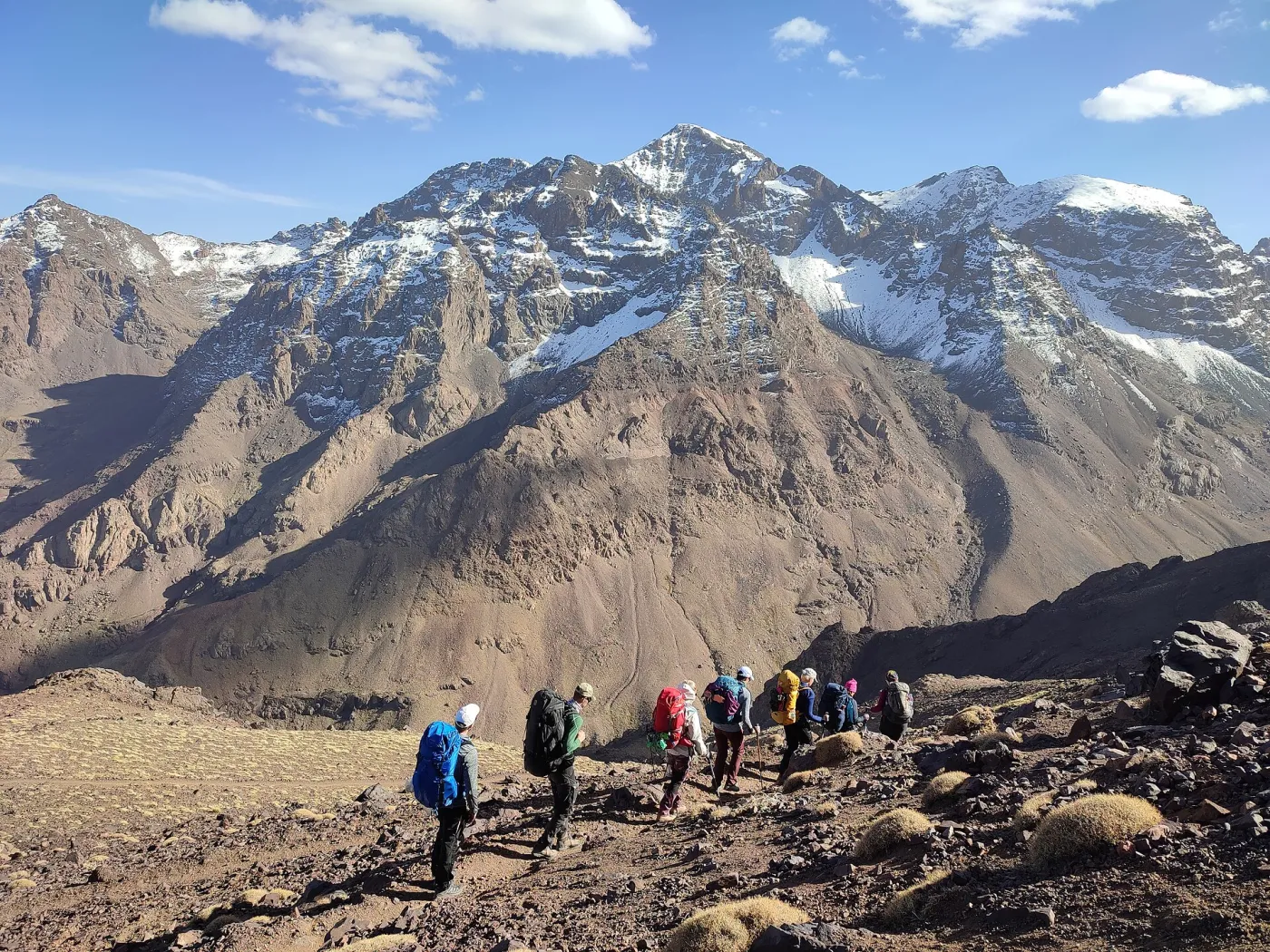 Hikers on the rocky ridge approaching the summit of Mount Toubkal at 4,167 m with the High Atlas peaks behind, Morocco